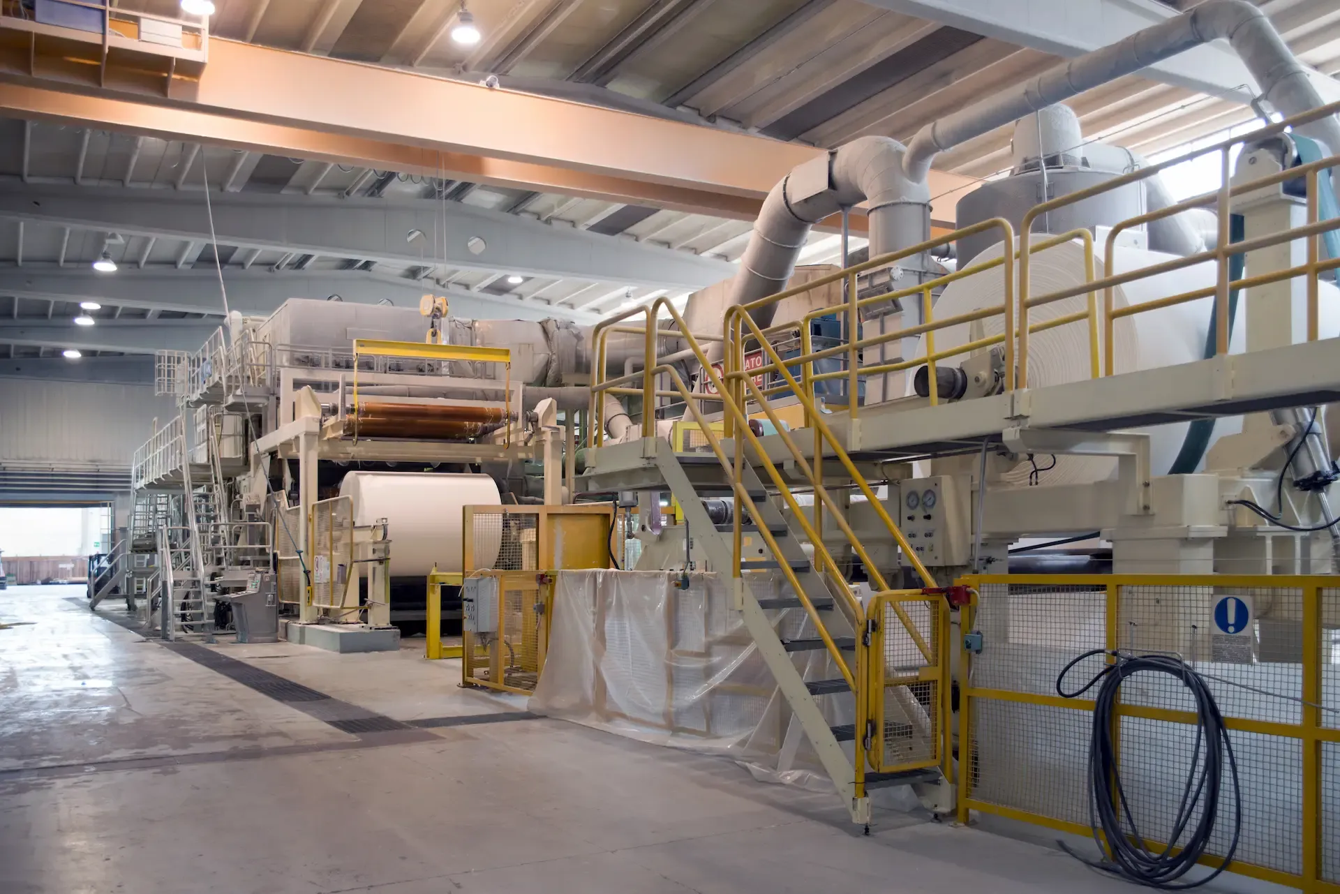 Línea de máquina papelera con pasarelas y bobina en una planta de celulosa y papel